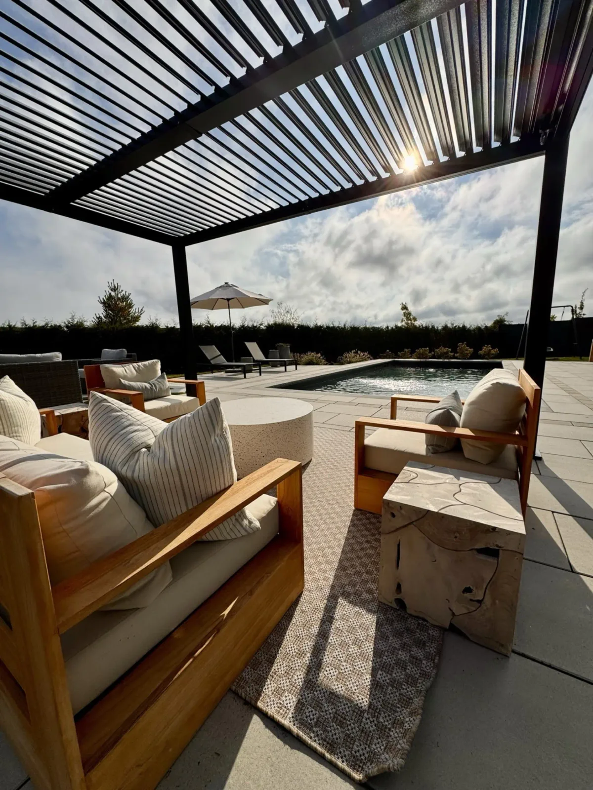 Louvered pergola sheltering a furnished poolside room