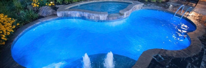 kidney bean shaped inground pool with attached hot tub spa and led lighting throughout