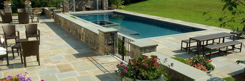 A contemporary pool with patio and landscaping, created by Edgewater Pools.