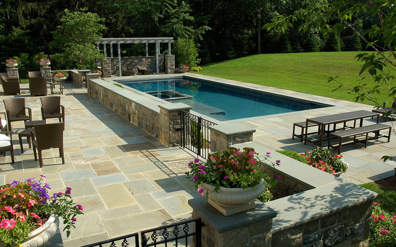 A contemporary pool with patio and landscaping, created by Edgewater Pools.