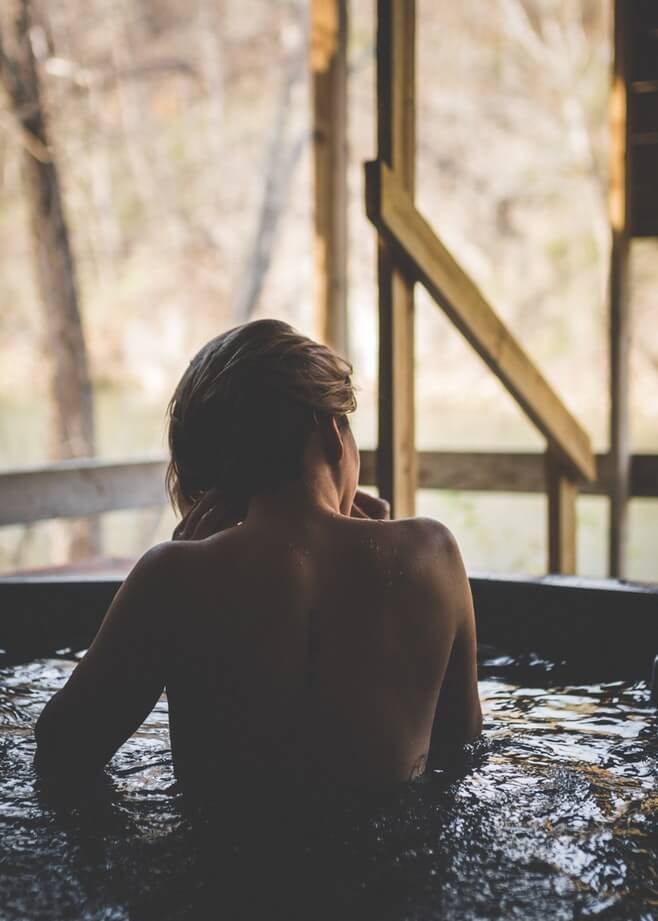 A woman looks out on her backyard from the comfort of a hot tub.