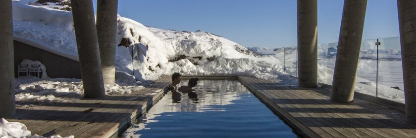 A couple sit in a a heated inground pool in the middle of winter.