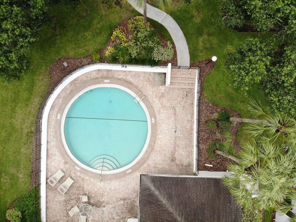 birds-eye view of circular inground pool with custom backyard landscaping