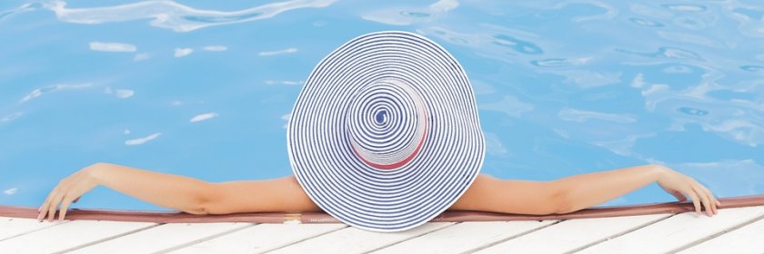 A woman in a sun hat reclines in a pool.