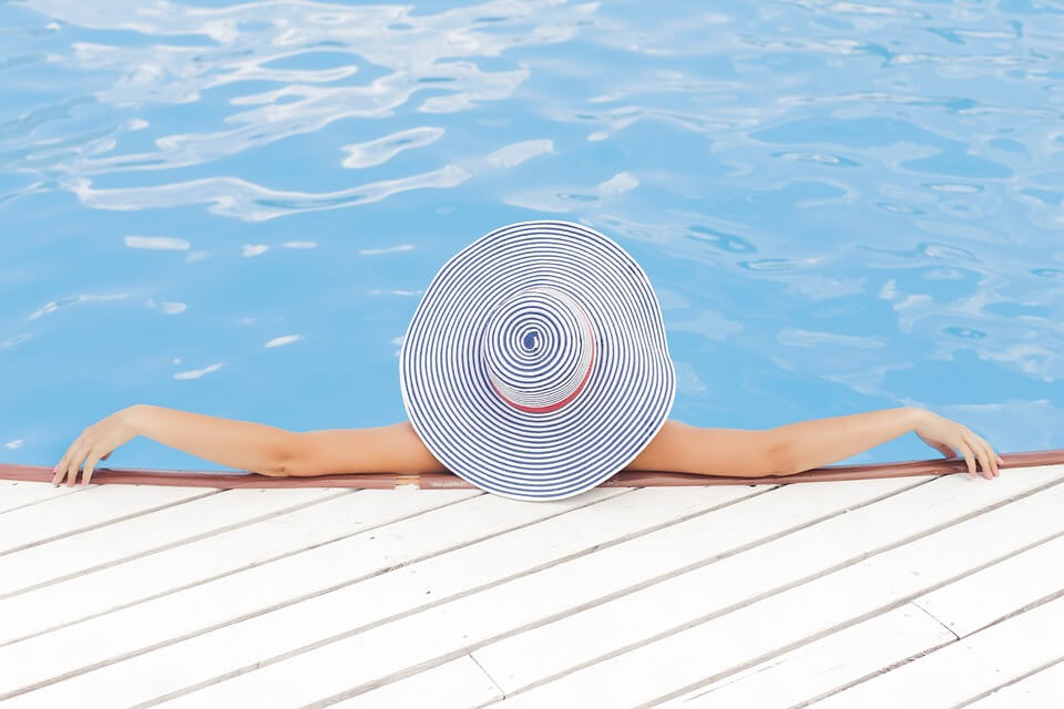 A woman in a sun hat reclines in a pool.