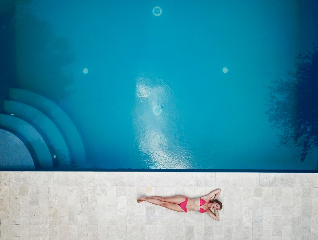Woman sunbathes next to her inground swimming pool