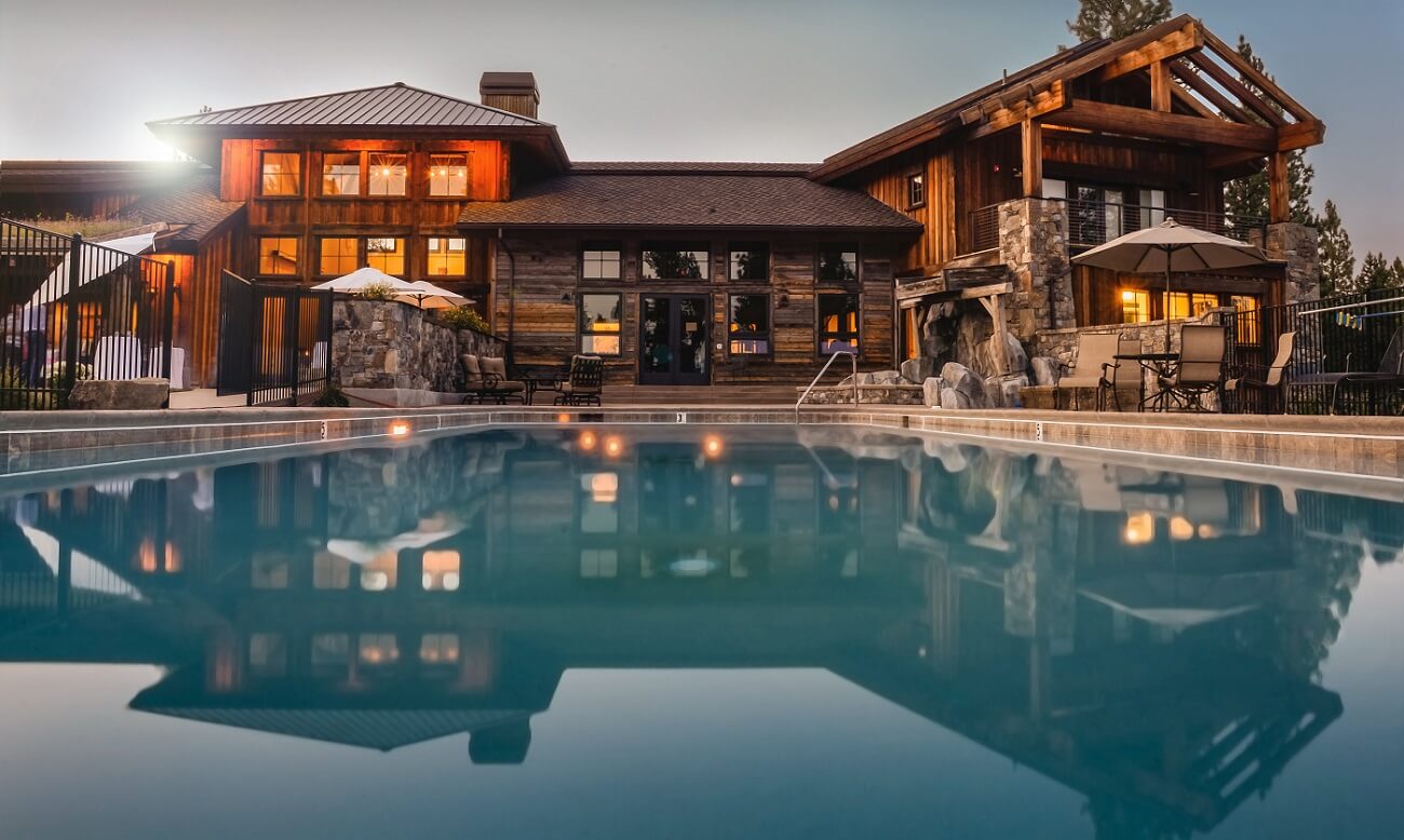 View of the backyard of a large modern home with a stunning inground pool