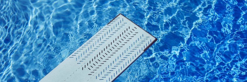 View of diving board above inground pool water