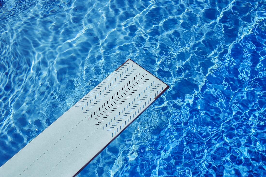 View of diving board above inground pool water