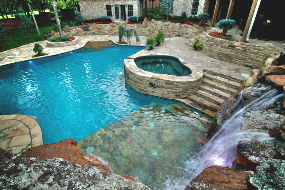 aerial view of luxury pool and spa in a unique shape with interlocking stone