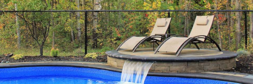 inground pool with spa and deck chairs enclosed by a fence