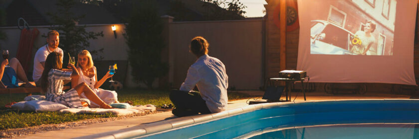 Friends enjoying a movie night in the backyard by the pool