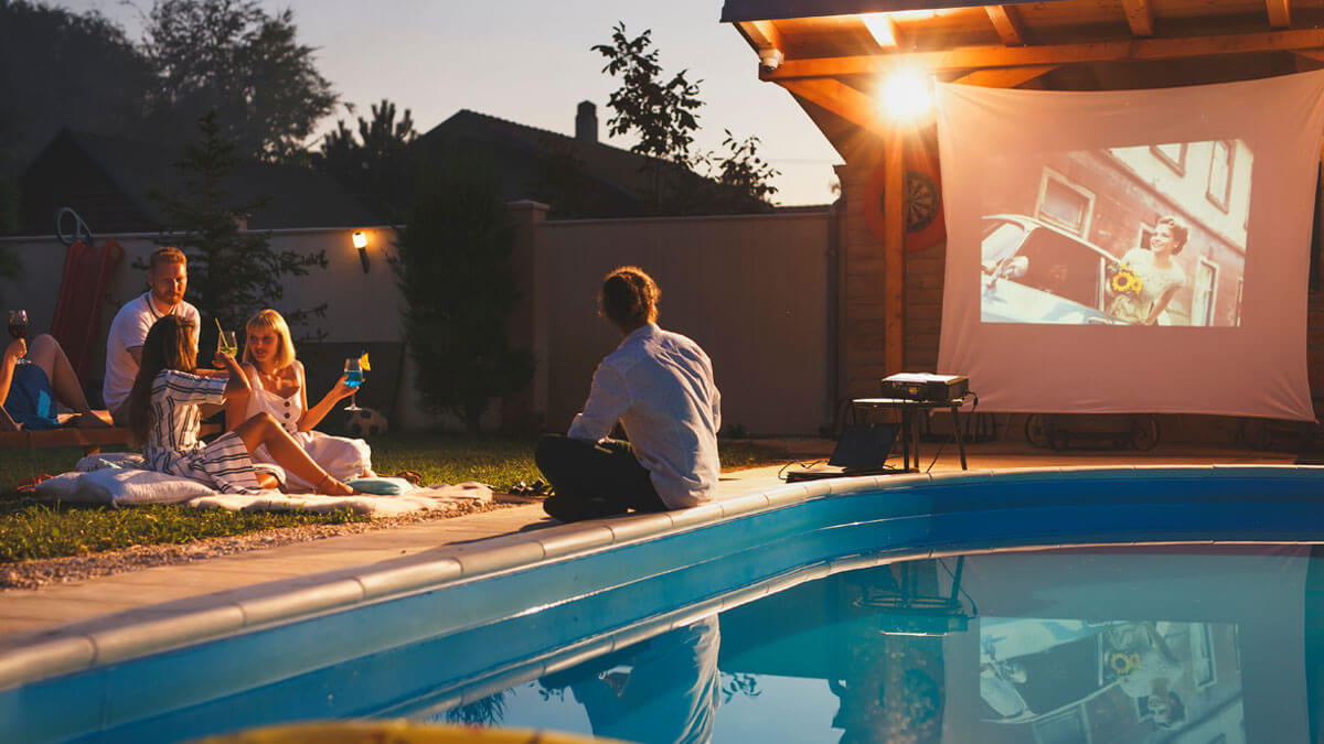 Friends enjoying a movie night in the backyard by the pool